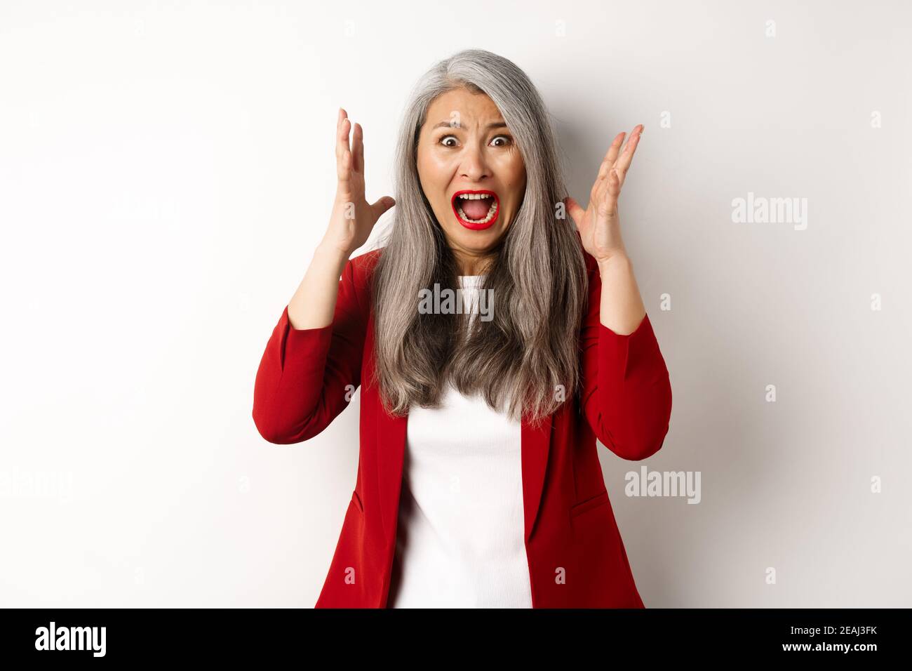 Femme d'affaires asiatique criant et regardant outragé, se sentant affligé et criant, debout contre fond blanc Banque D'Images