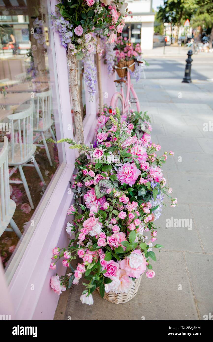Vue portrait de fleurs artificielles en dehors de la fenêtre d'un Boutique de gâteaux roses Banque D'Images