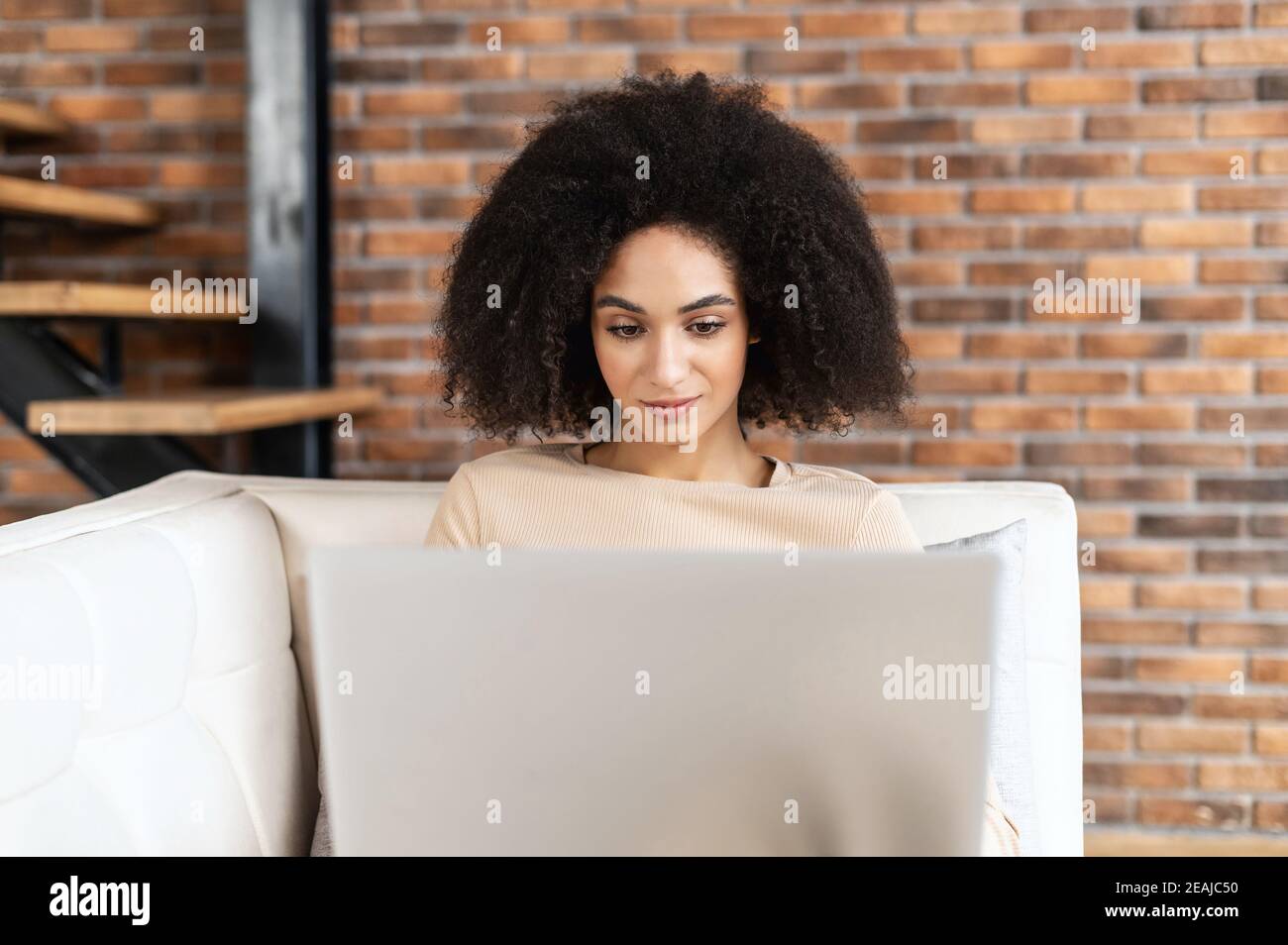 Portrait d'une jeune femme d'affaires de race mixte ou d'une femme indépendante Avec la coiffure afro en position allongée sur le canapé et travailler sur le projet Banque D'Images