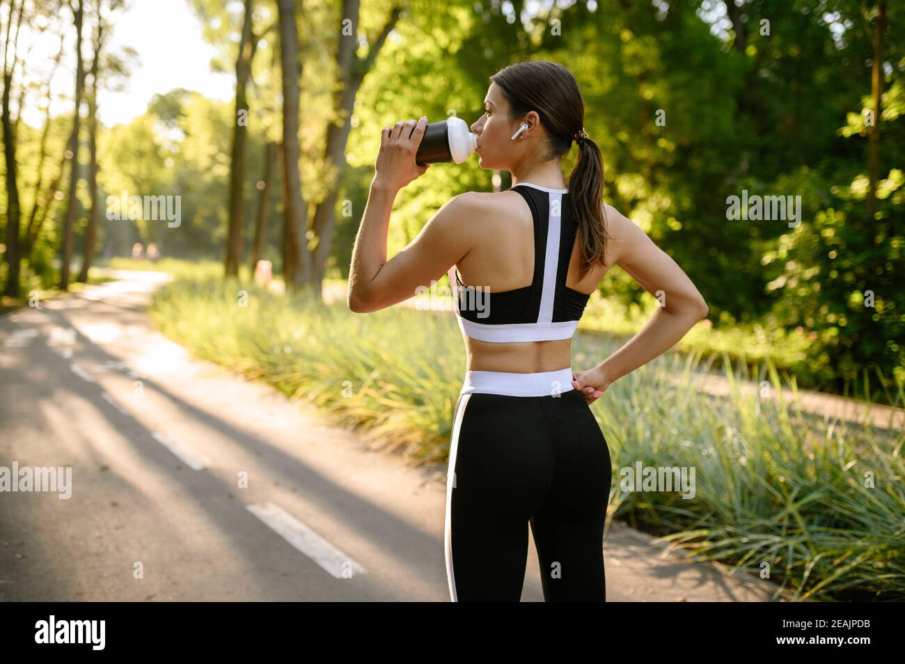 Entraînement matinal dans le parc, femme boit de l'eau Banque D'Images