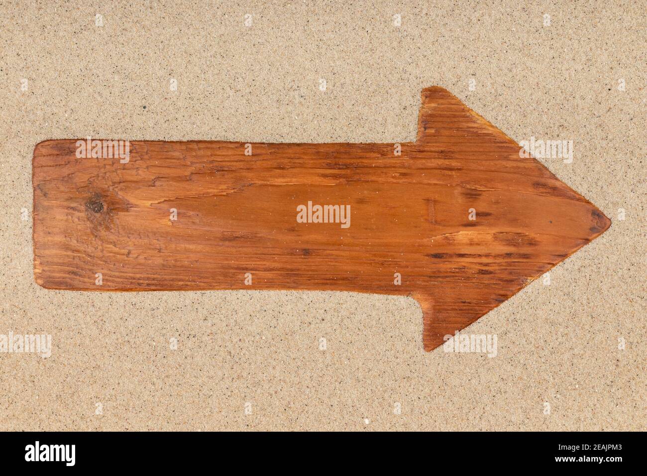Flèche faite d'une vieille planche de bois sur le sable. Banque D'Images