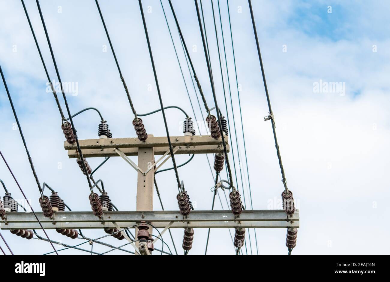 Alimentation électrique triphasée pour le transfert de puissance par les réseaux électriques. L'énergie électrique pour soutenir l'industrie de fabrication. Poteaux électriques haute tension et lignes de fils contre le ciel bleu et les nuages blancs. Banque D'Images