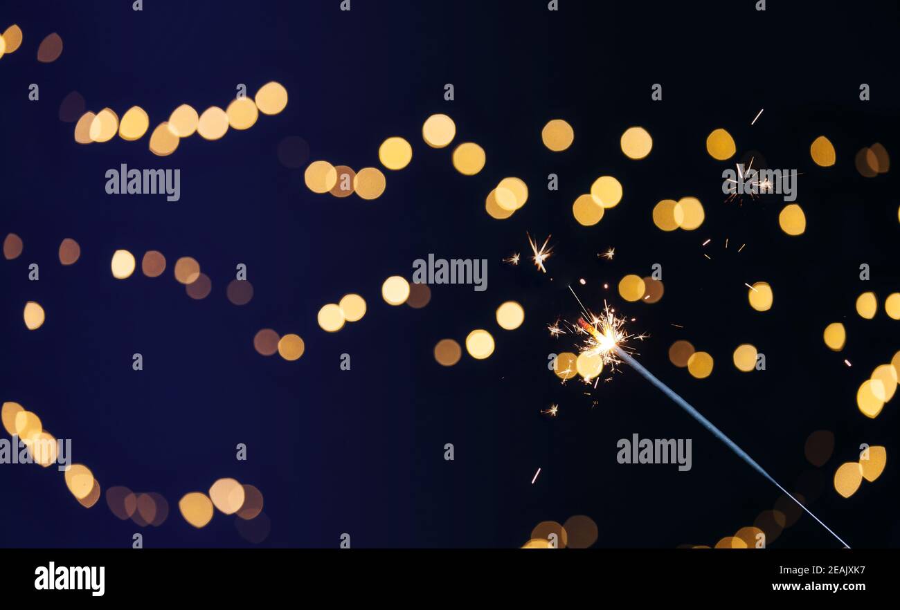 Sparkler brûlant avec fond de bokeh festif pour le nouvel an et le concept de Noël, espace pour le texte Banque D'Images