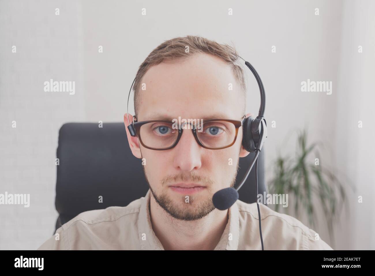 Jeune femme séduisante avec un sourire amical portant un casque pour la communication en ligne en tant que client virtuel professionnel de l'aide ou un service à la clientèle Banque D'Images