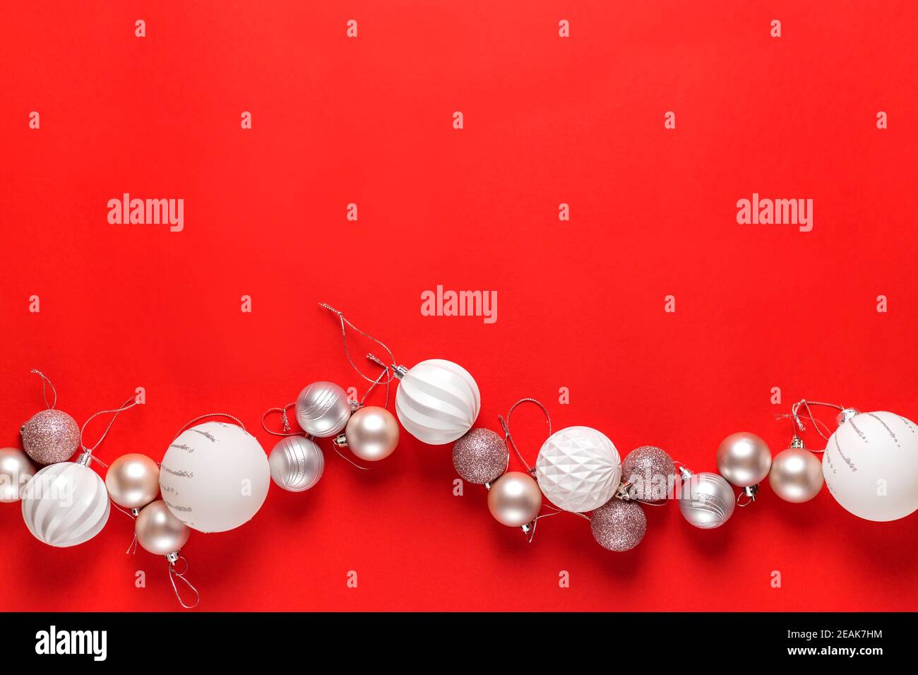 Décoration blanche de boules de noël sur fond rouge. Pose à plat. Concept de vacances. Banque D'Images