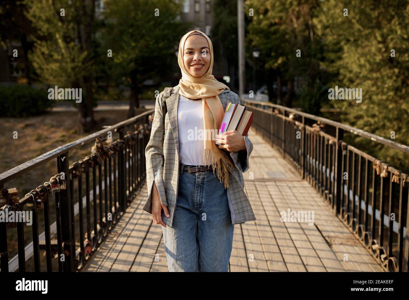 Une fille arabe dans le hijab tient des manuels scolaires dans le parc d'été Banque D'Images