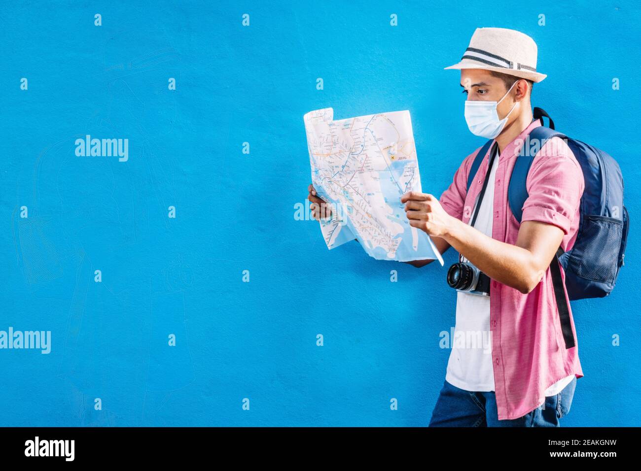 homme adulte avec un sac à dos portant un masque tenant et regarder une carte.f Banque D'Images