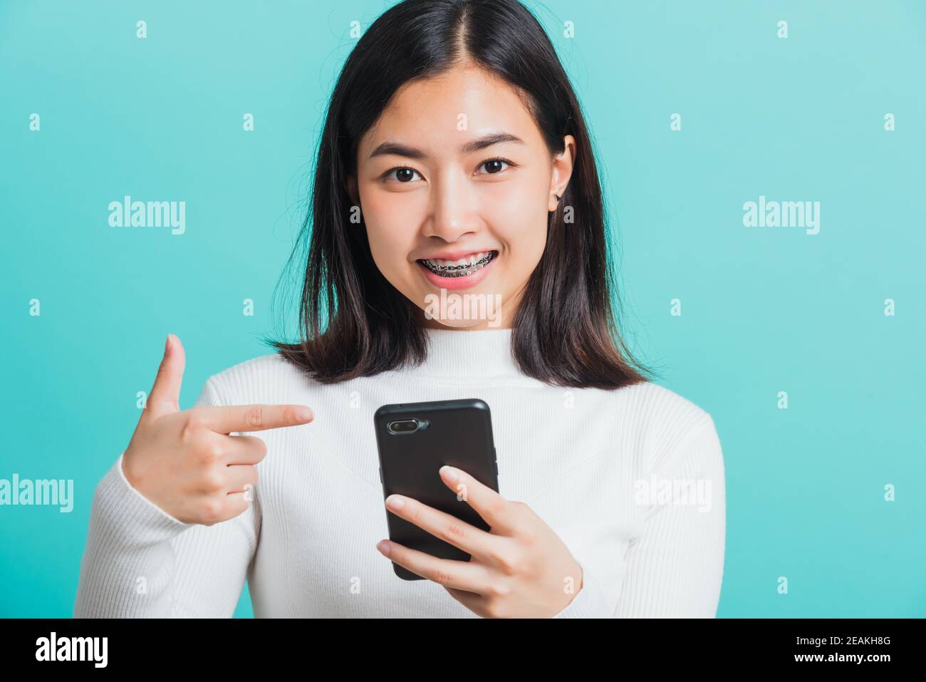 une femme sourit qu'elle pointe le doigt vers un smartphone Banque D'Images