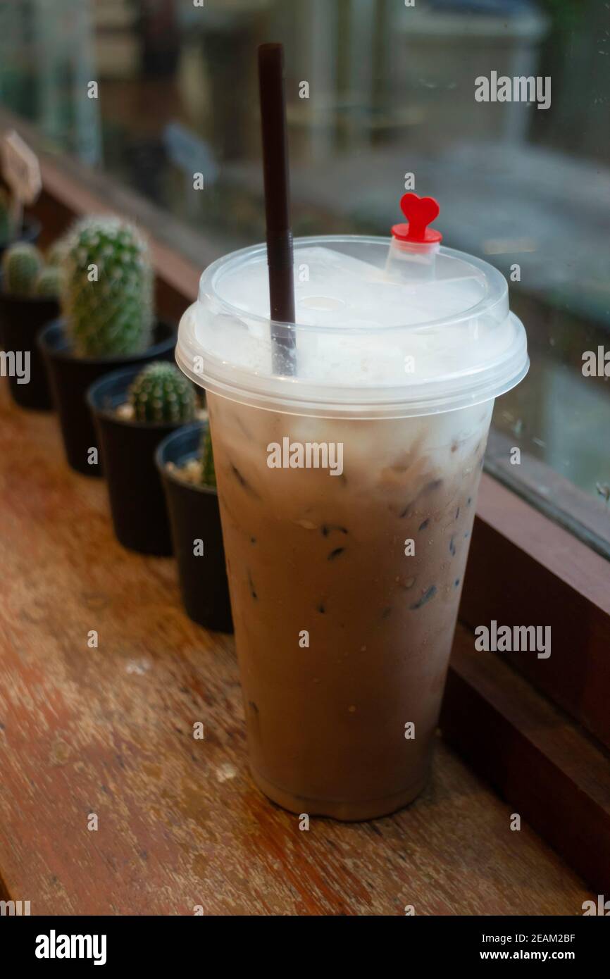 Café au lait glacé dans une tasse jetable sur une table en bois Banque D'Images