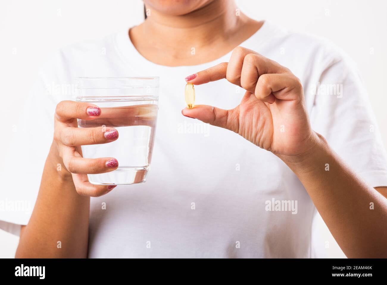 Femme tenir les médicaments de vitamine d'huile de poisson dans la main prêt à prendre médicaments avec un verre d'eau Banque D'Images