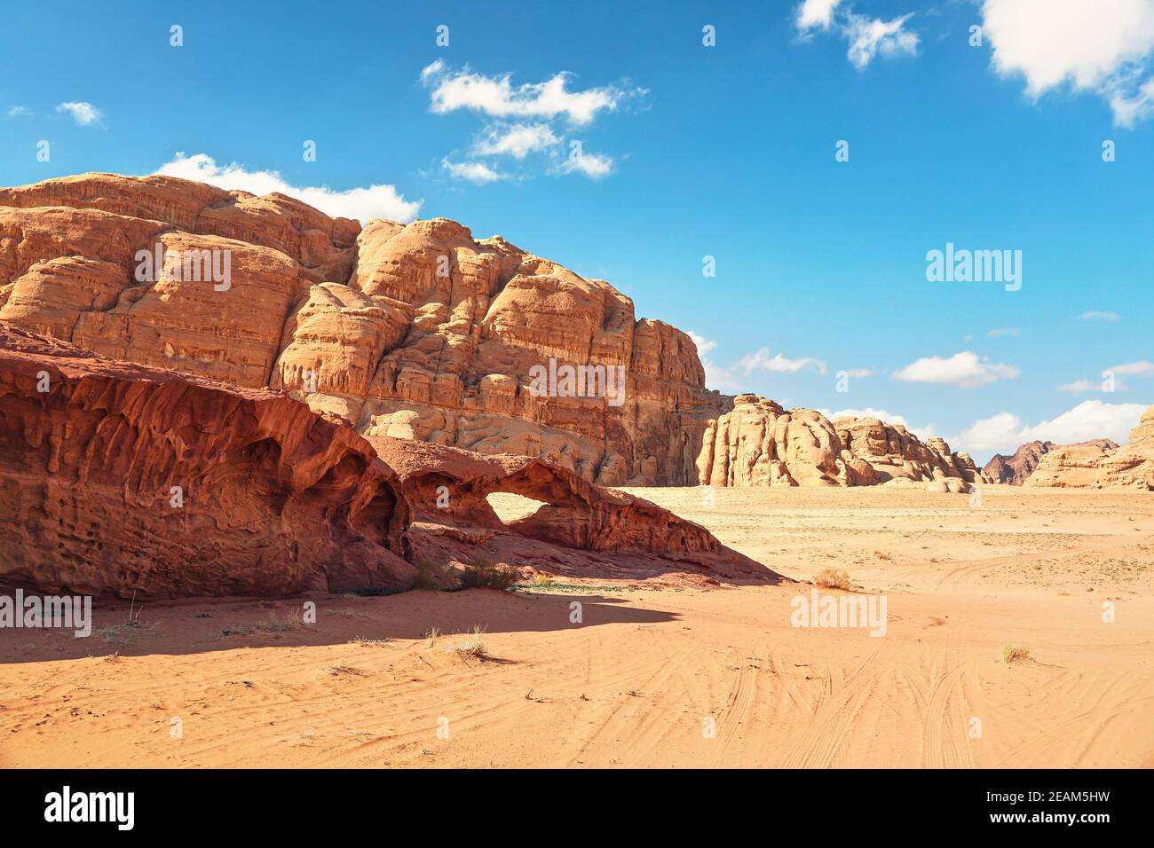 Massifs rocheux sur désert de sable rouge, petit pont d'arc en pierre, ciel bleu clair en arrière-plan - paysage typique à Wadi Rum, Jordanie Banque D'Images