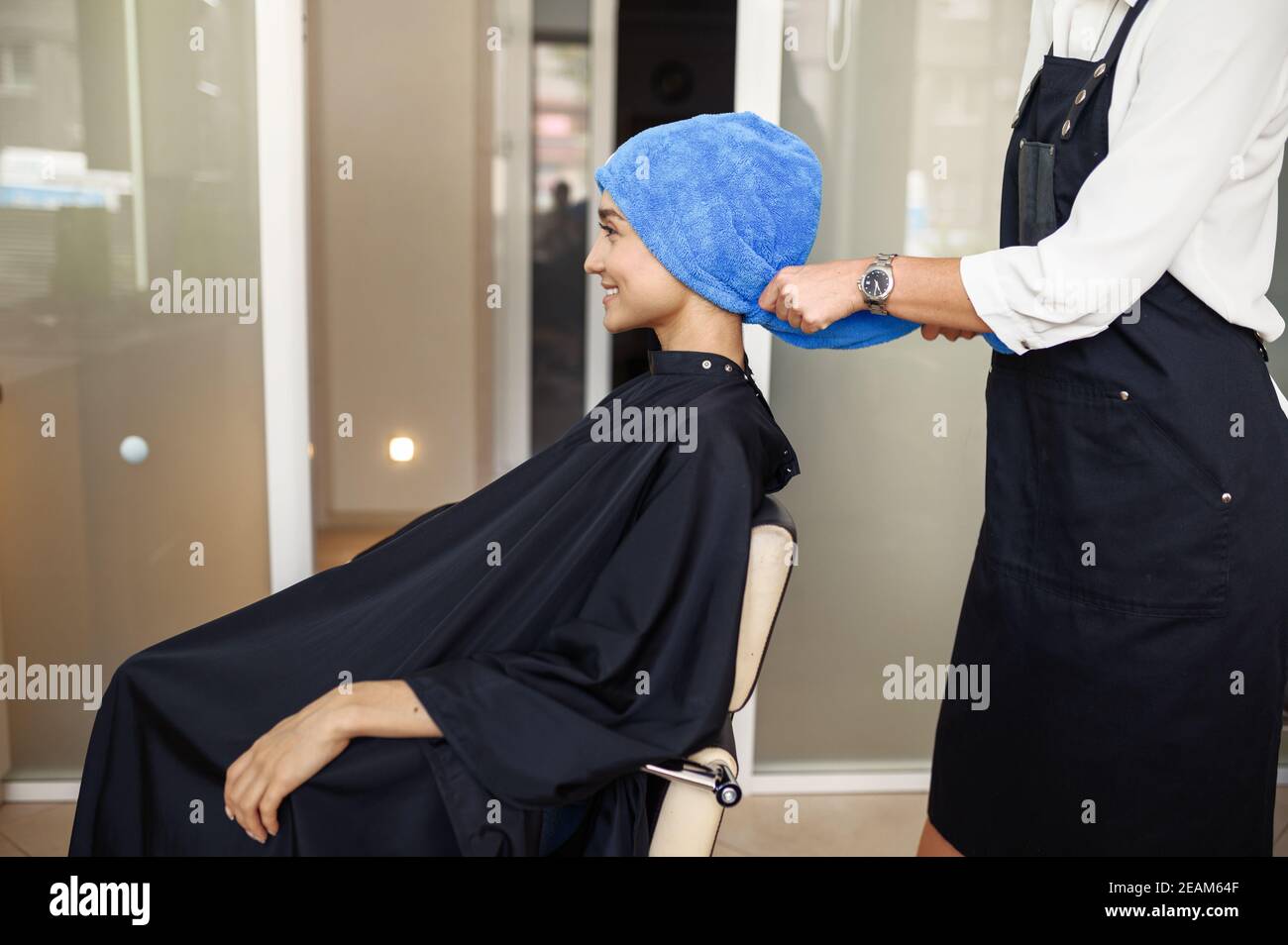 Coiffeur met une serviette sur les cheveux de la femme, salon de coiffure Banque D'Images