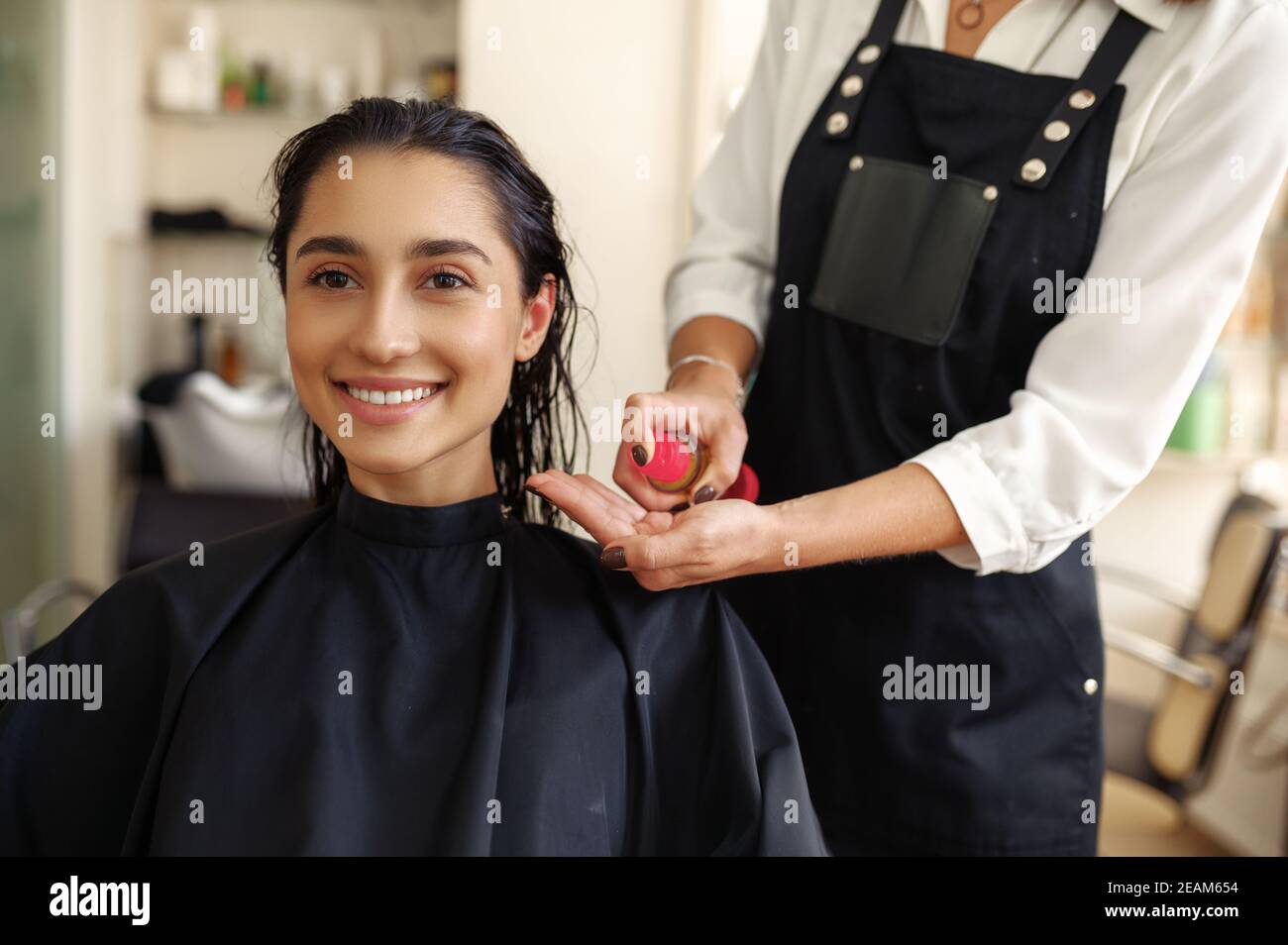 Le coiffeur applique de la mousse sur les cheveux de la femme Banque D'Images
