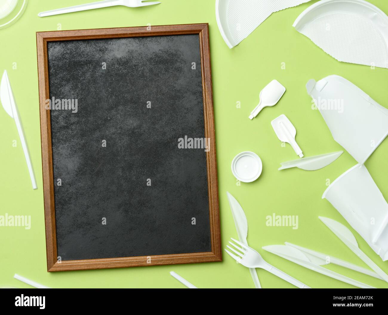cadre en bois vide et vaisselle en plastique blanc cassé sur vert arrière-plan Banque D'Images