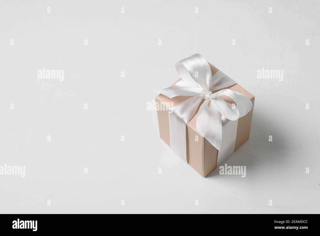 Boîte cadeau beige avec noeud sur fond blanc Banque D'Images