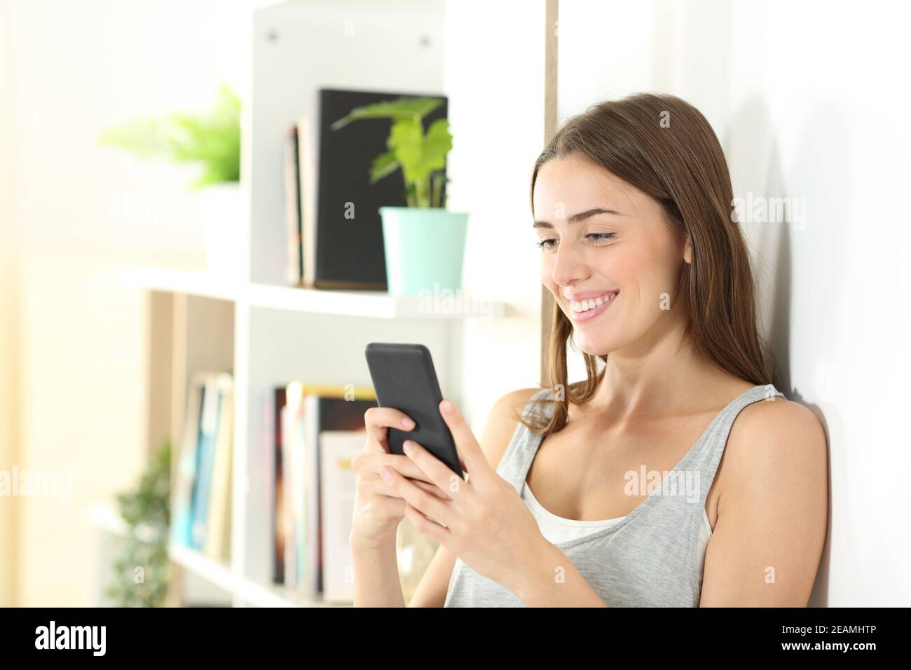 L'adolescent heureux utilise un smartphone à la maison Banque D'Images