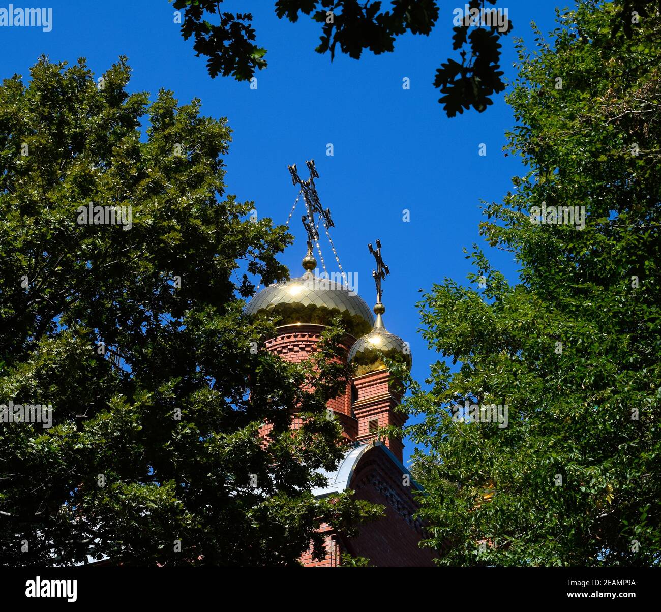 Dôme de l'Église orthodoxe avec des croisements, vue à travers les branches d'arbres contre le ciel bleu Banque D'Images