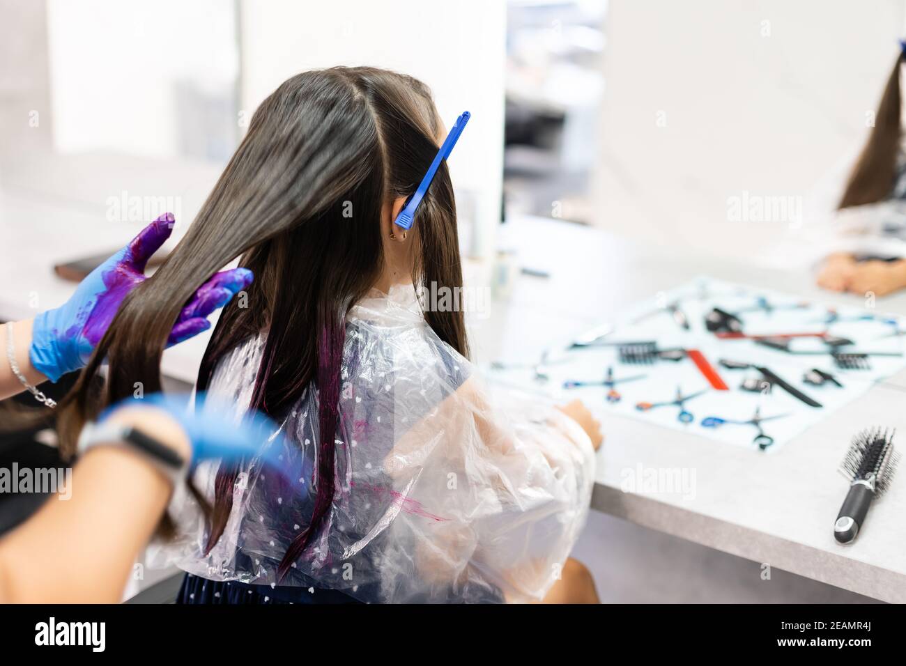 une petite fille teint ses cheveux violets dans un salon de coiffure Banque D'Images