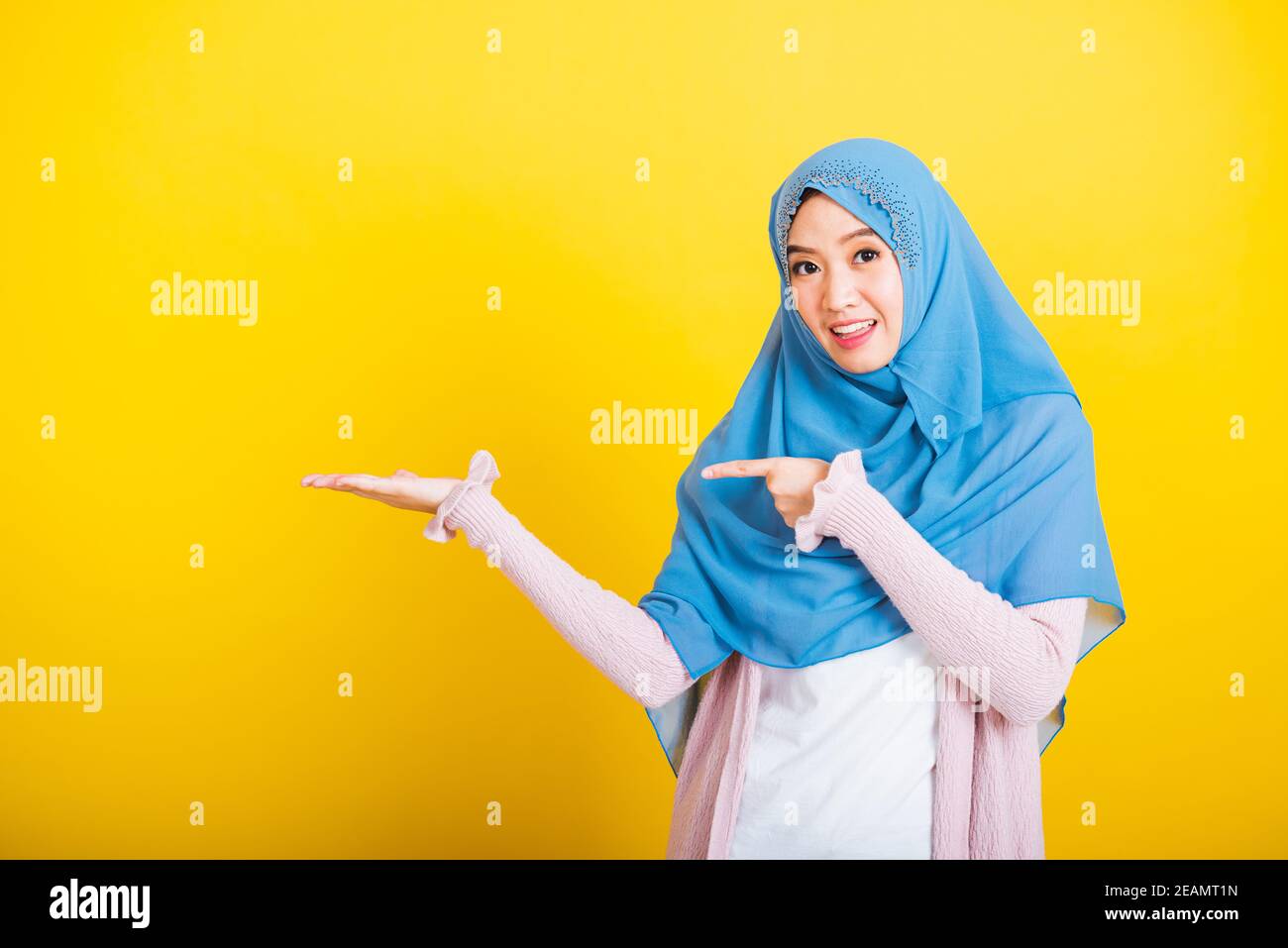 Asiatique musulmane arabe femme Islam porter hijab sourire elle positive expression pointant vers le côté du doigt Banque D'Images