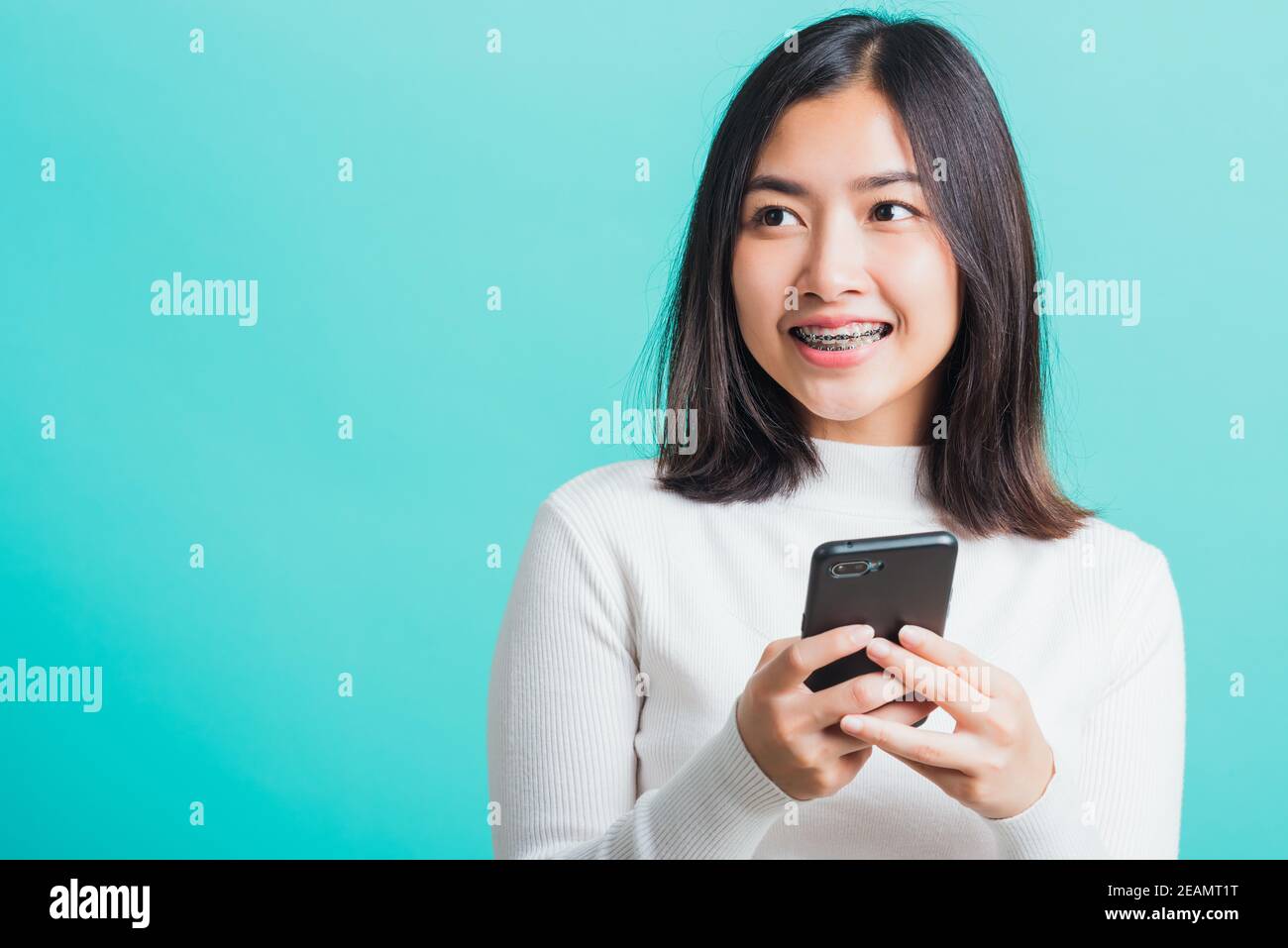 une femme sourit qu'elle tient et tape un message texte Banque D'Images