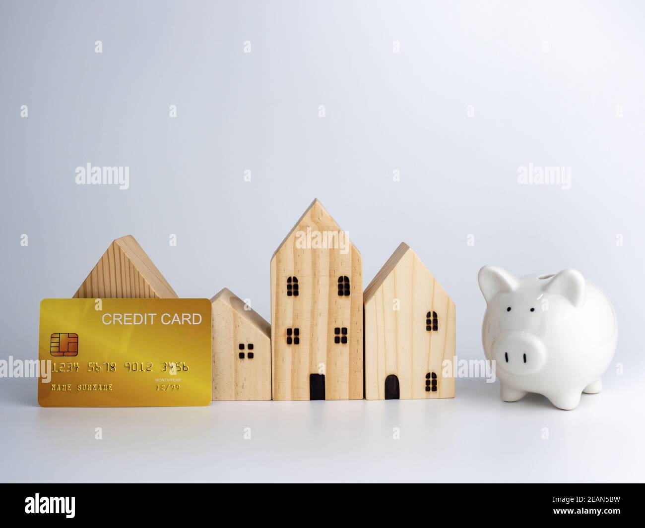 Modèle de maison en bois et de piggy banque et carte de crédit sur un fond blanc. Concept d'entreprise de logement. Banque D'Images