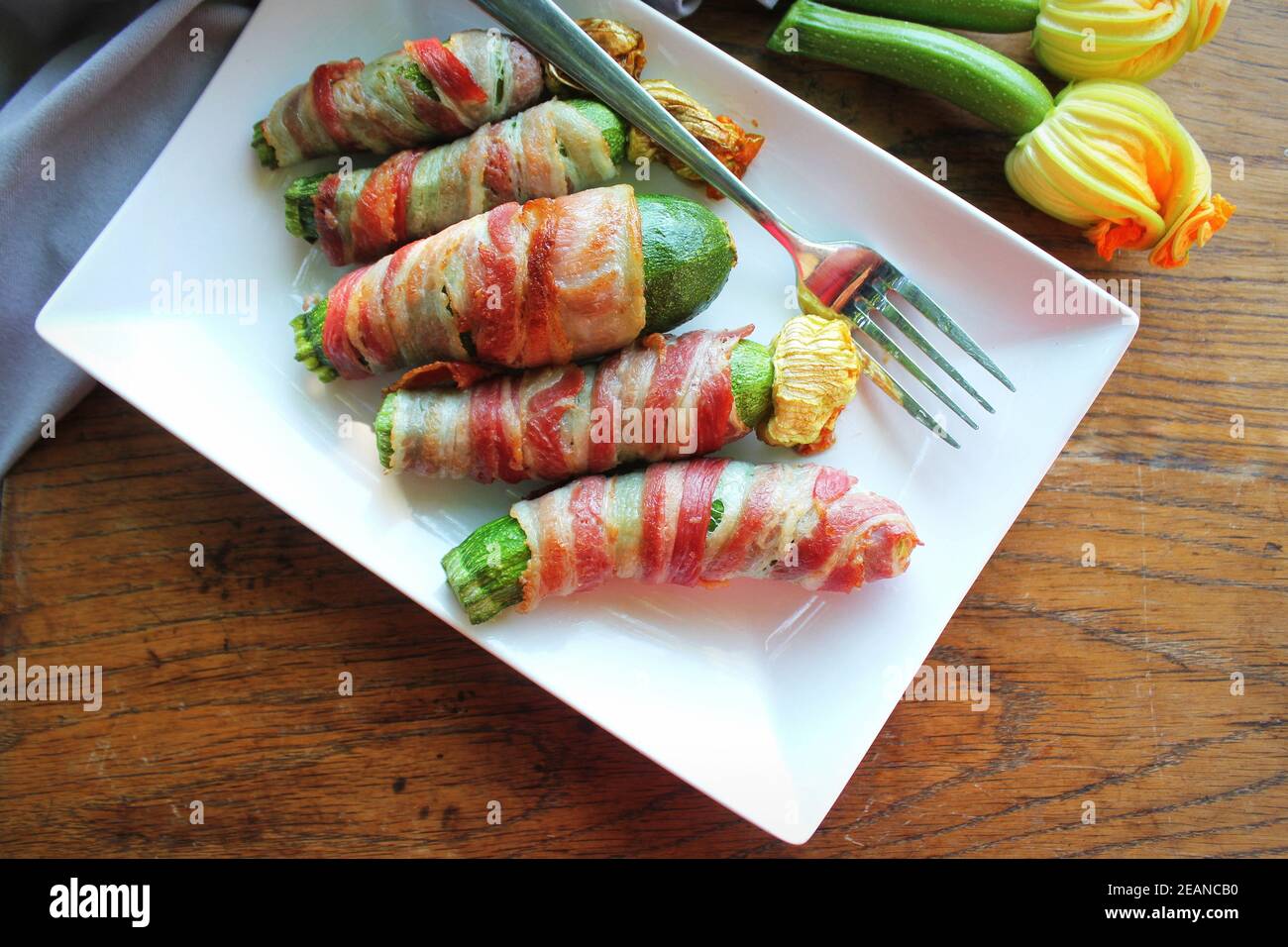 Des courgettes grillées enveloppées dans un bacon sur une plaque blanche Banque D'Images