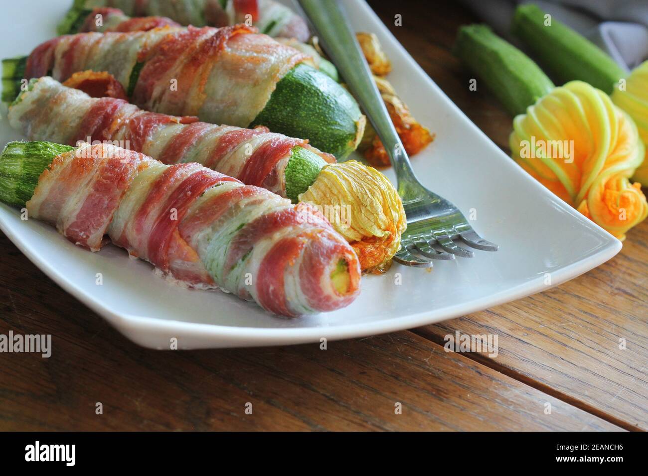 Des courgettes grillées enveloppées dans un bacon sur une plaque blanche Banque D'Images