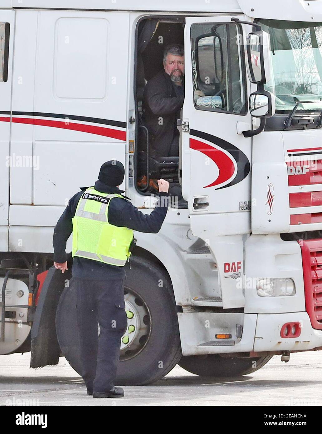 Un officier de la Force frontalière s'entretient avec un chauffeur de camion au site du ministère de l'Agriculture, de l'Environnement et des Affaires rurales, sur la rue Duncrue, près du port de Belfast, alors que les contrôles post-Brexit reprennent dans tous les ports d'Irlande du Nord. Les inspections des produits alimentaires à base d'animaux arrivant aux ports de Belfast et de Larne ont été suspendues en raison de préoccupations concernant la sécurité du personnel. Date de la photo: Mercredi 10 février 2021. Banque D'Images