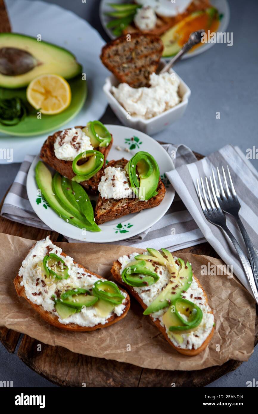 Sandwichs au fromage doux, à l'avocat et au concombre. Le petit déjeuner est sur la table. Une alimentation saine. Toasts et tartiner dessus. Sandwich avocat mortivie. Santé Banque D'Images