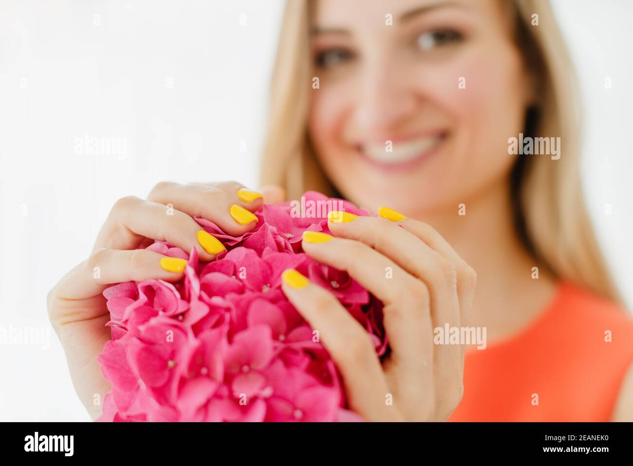 Femmes avec ongles manucurés en jaune tenant une fleur Banque D'Images