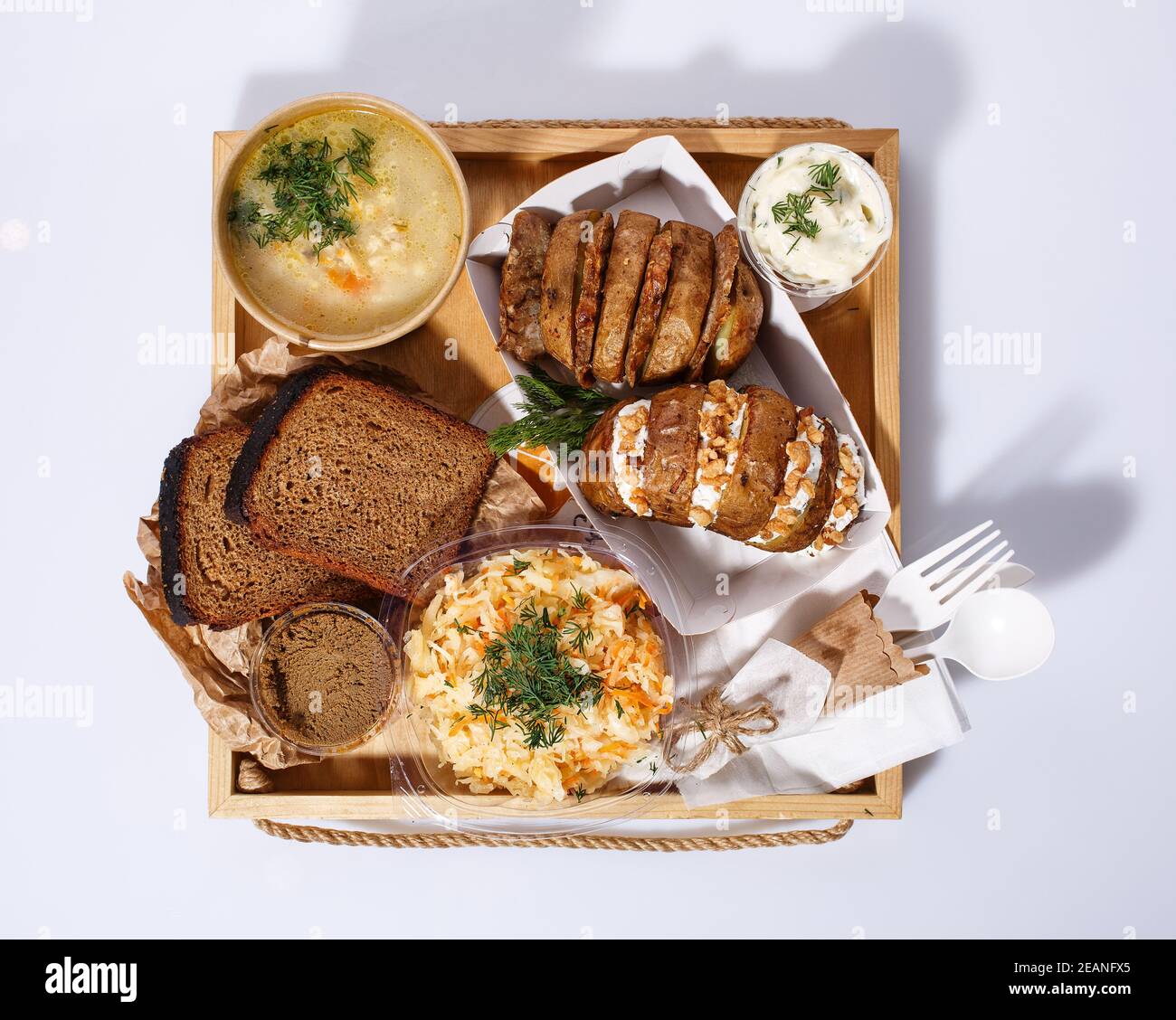 Soupe de légumes dans une tasse jetable, pommes de terre cuites au four avec du fromage et des noix dans une boîte en papier, pain, pate, sauce à la crème Banque D'Images