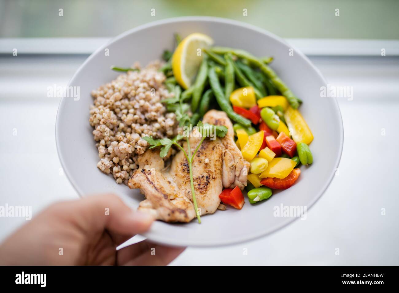 Main tenant un plat de poulet et de sarrasin avec des haricots verts Banque D'Images