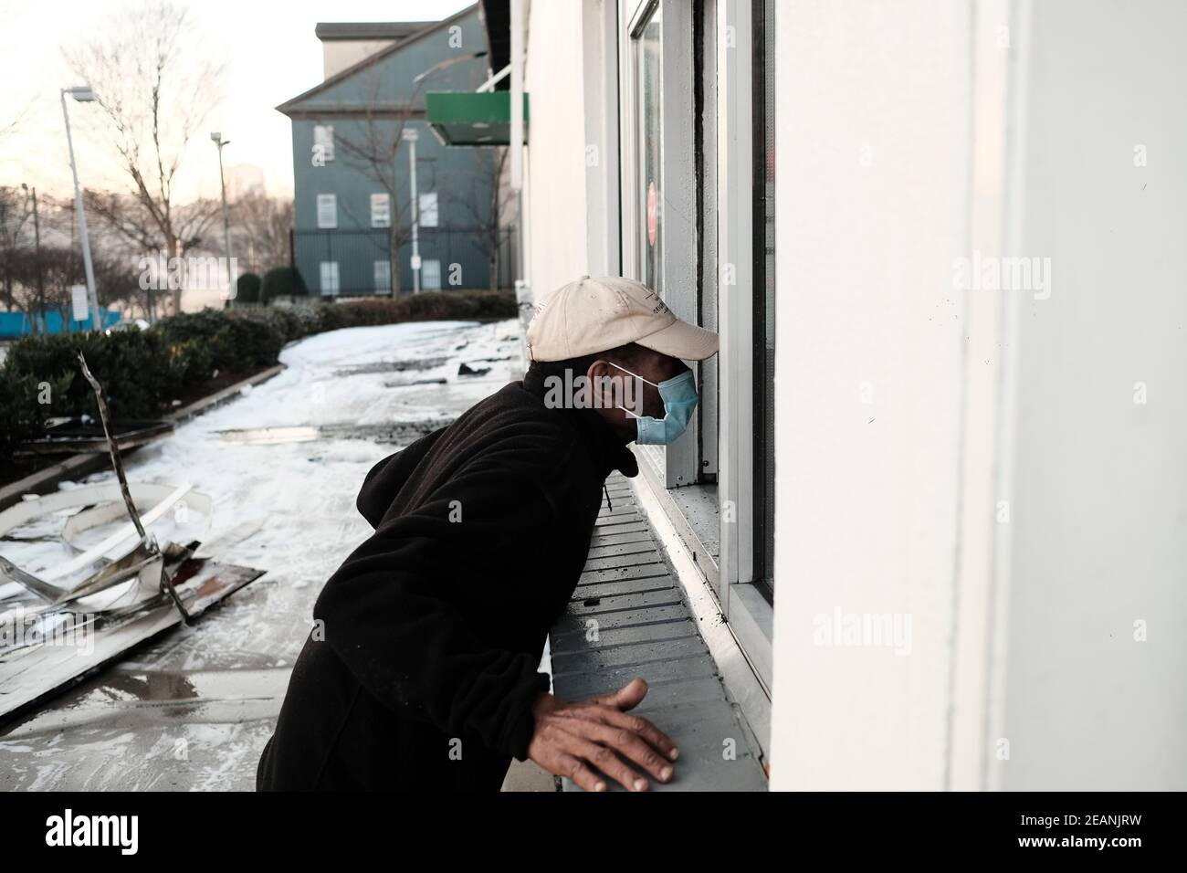 Atlanta, Géorgie, États-Unis. 10 février 2021. Maurice Sutton, un employé de Krispy Kreme de 20 ans, regarde à l'intérieur d'une fenêtre de la boutique de beignets brûlés sur Ponce de Leon Ave à Atlanta qui a pris feu tôt mercredi matin. « Ma deuxième maison », dit-il. La boutique a été construite en 1965 et depuis des années a été un point de repère. La salle NBA de famer Shaquille O'Neal est devenue propriétaire de la boutique en 2016. Crédit : John Arthur Brown/ZUMA Wire/Alay Live News Banque D'Images