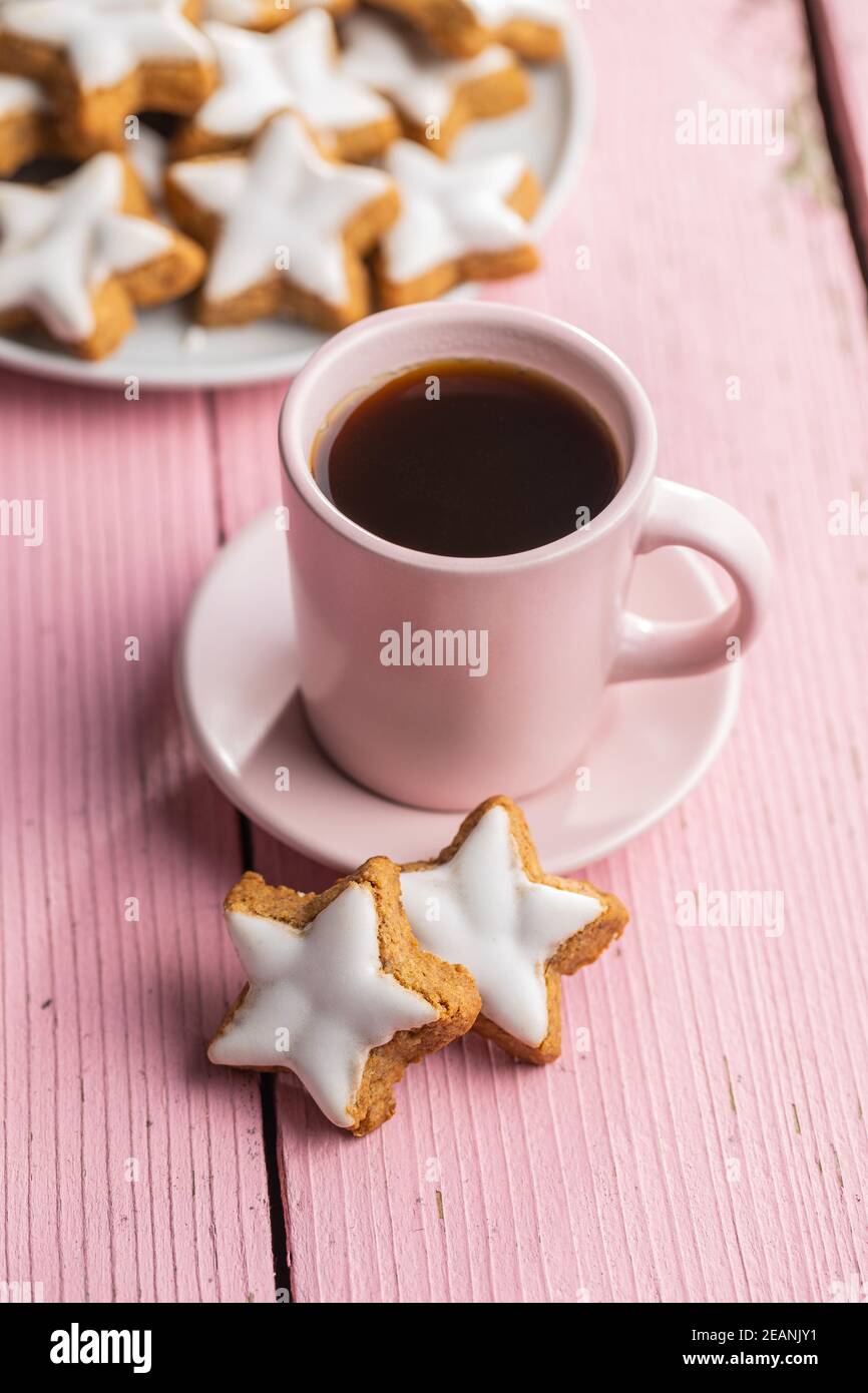 Le glaçage des étoiles de pain d'épice. Biscuits de Noël traditionnels sur une table en bois rose. Banque D'Images