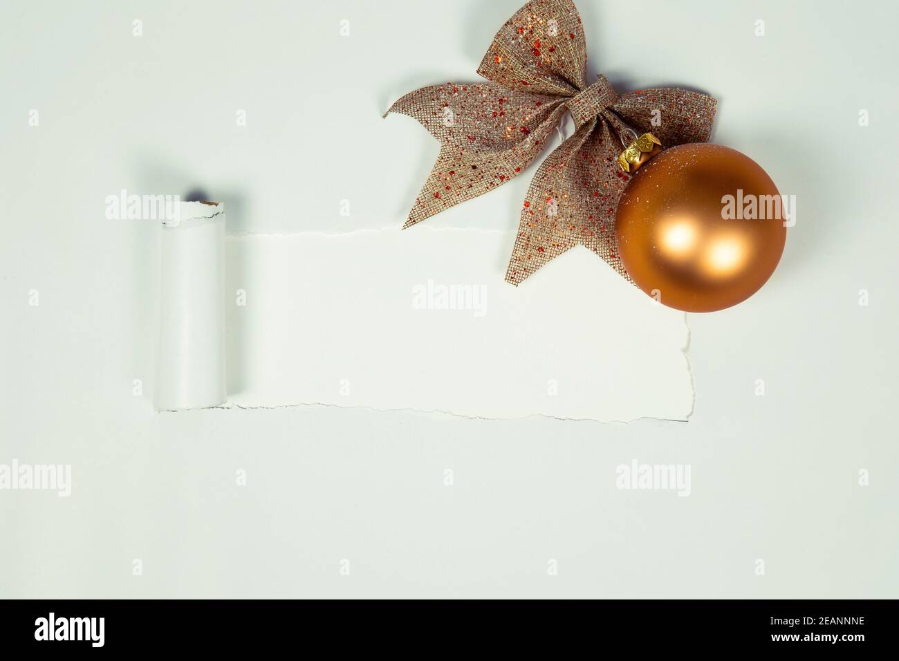 Boule de Noël dorée avec noeud étincelant vue sur le dessus avec papier déchiré pour l'espace de copie ou espace pour texte vue sur le dessus isolée sur fond blanc, beau design de Noël minimaliste Banque D'Images