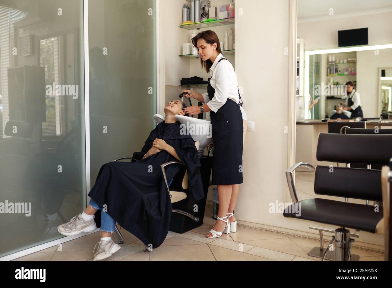 Coiffeur lave les cheveux de la femme, salon de coiffure Banque D'Images