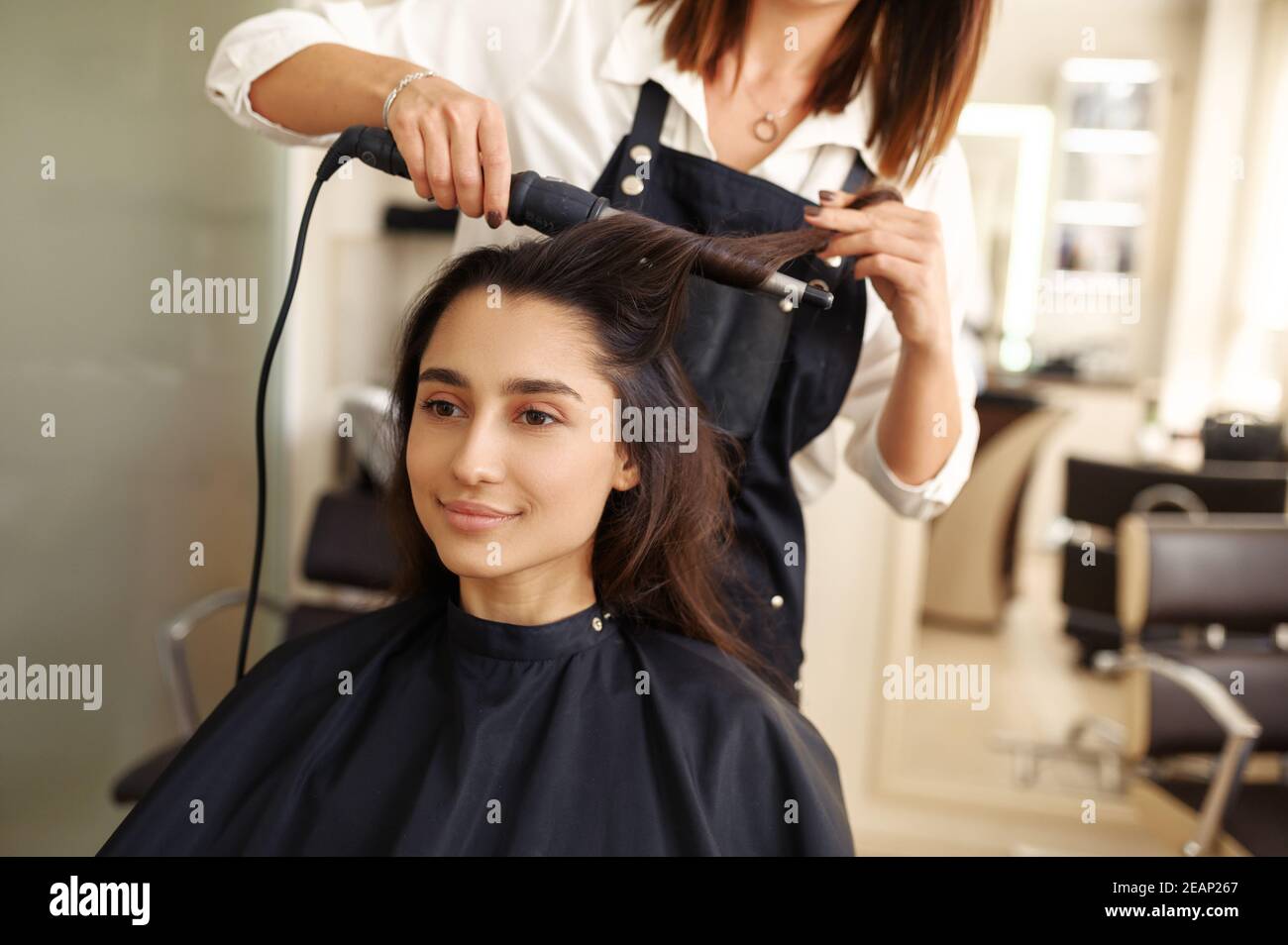 Le coiffeur curls les cheveux de la femme, salon de coiffure Banque D'Images