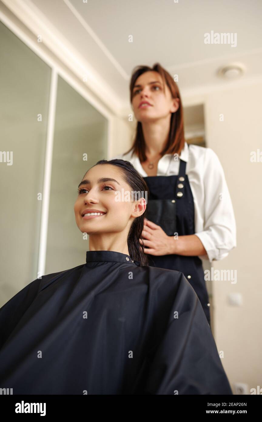 Le coiffeur applique de la mousse sur les cheveux de la femme Banque D'Images