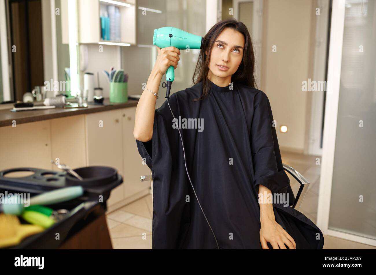 La cliente met un sèche-cheveux à la tête, salon de coiffure Banque D'Images