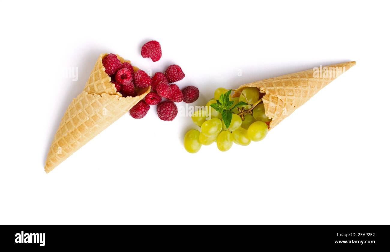 Framboises fraîches et raisins dans des cornets de gaufres Banque D'Images