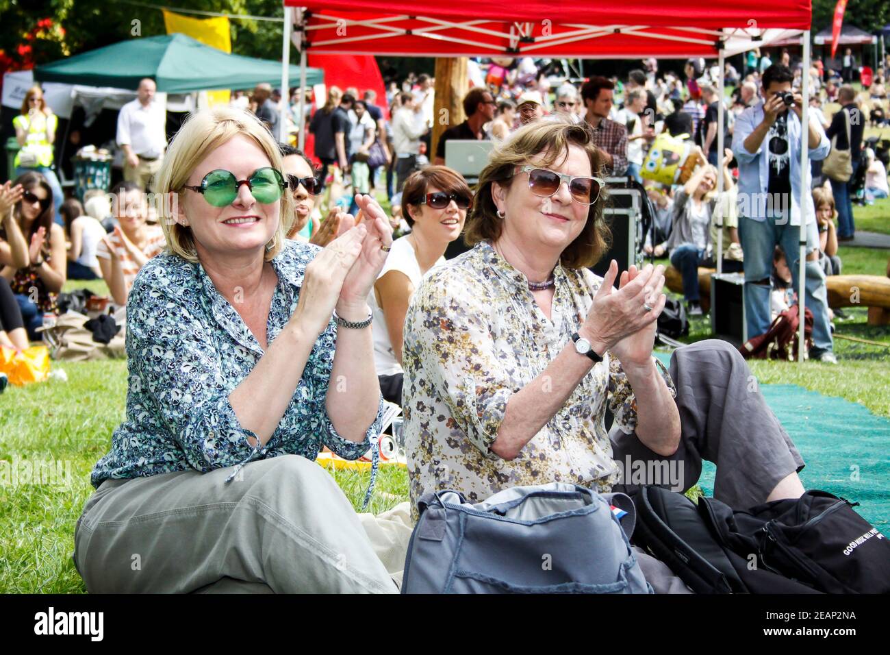 Deux dames assises sur l'herbe, regardant un spectacle et des applaudissements au festival souterrain de Crystal Palace, dans le sud de Londres Banque D'Images