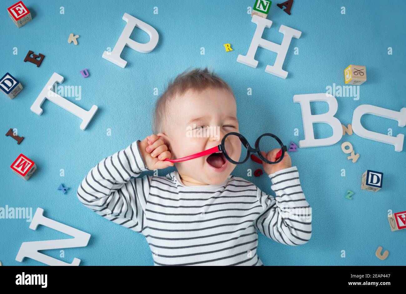 Un an enfant couché avec des lunettes et des lettres Banque D'Images