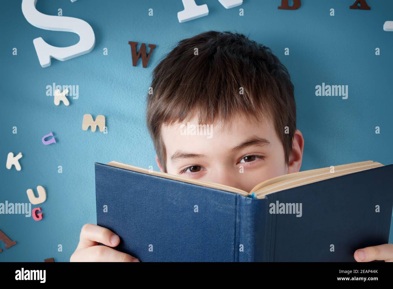 Sept ans enfant couché avec livre et lettres Banque D'Images