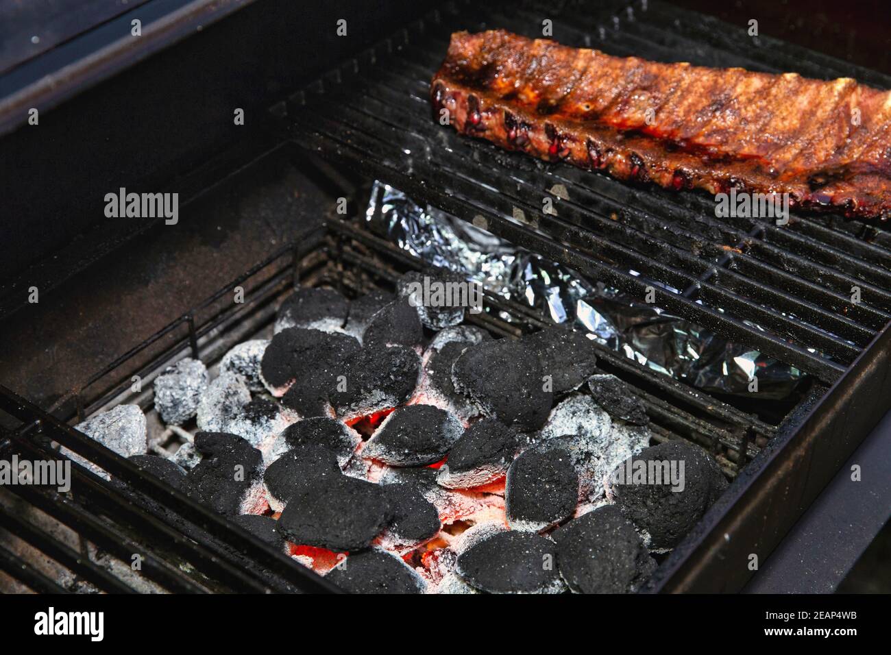 Gros plan de torréfaction barbecue et de péleribs fumés au porc émaillés de sauce sur le gril chaud au charbon de bois avec flammes, barbecue et concept hobby Banque D'Images