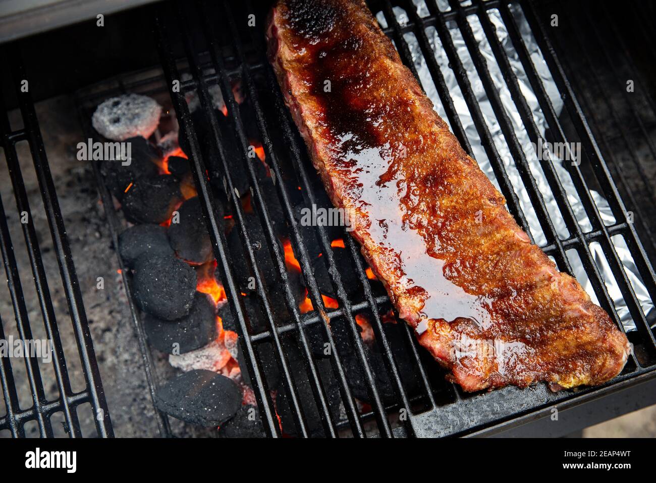 Gros plan de torréfaction barbecue et de péleribs fumés au porc émaillés de sauce sur le gril chaud au charbon de bois avec flammes, barbecue et concept hobby Banque D'Images