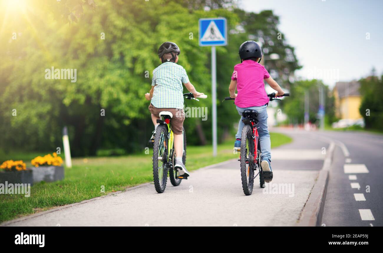 Les enfants avec des sacs à dos équitation sur des vélos dans le parc près de l'école Banque D'Images