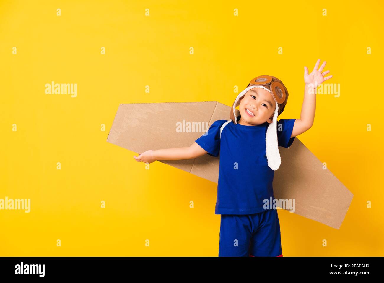 Enfant petit garçon sourire porter un chapeau de pilote jouer et des lunettes avec ailes d'avion en carton Banque D'Images