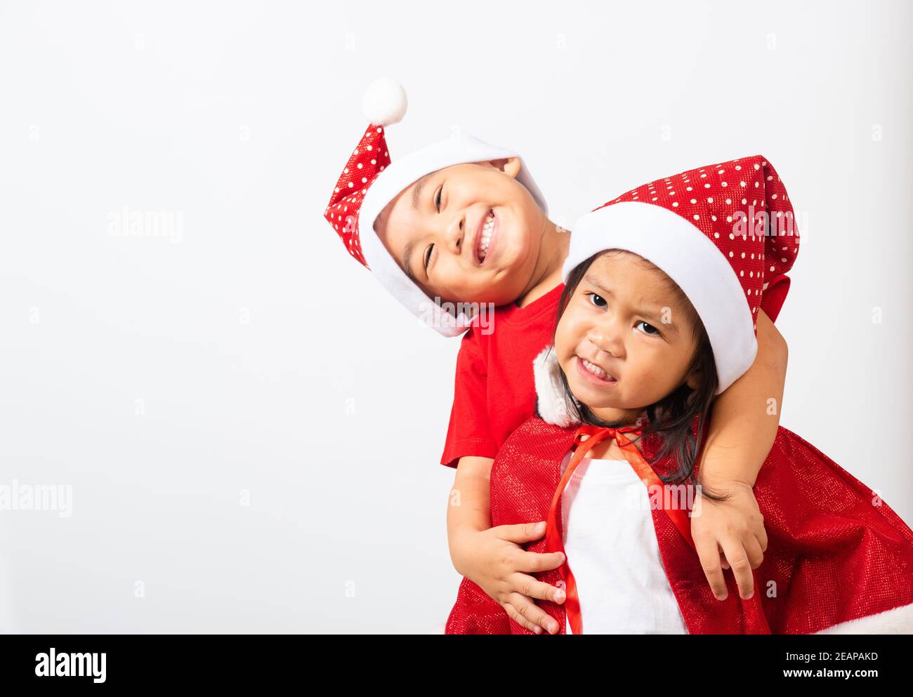 Les enfants vêtus d'un chapeau de père Noël rouge s'embrassant ensemble Banque D'Images