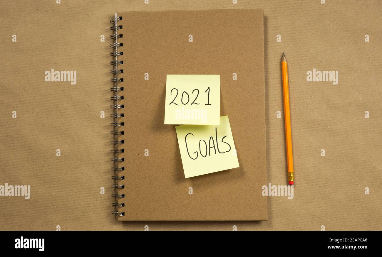 Carnet avec notes adhésives jaunes avec 2021 et objectifs pour le nouvel an sur fond de papier brun avec un concept classique de crayon, d'affaires ou d'école, d'éducation. Copier l'espace Banque D'Images