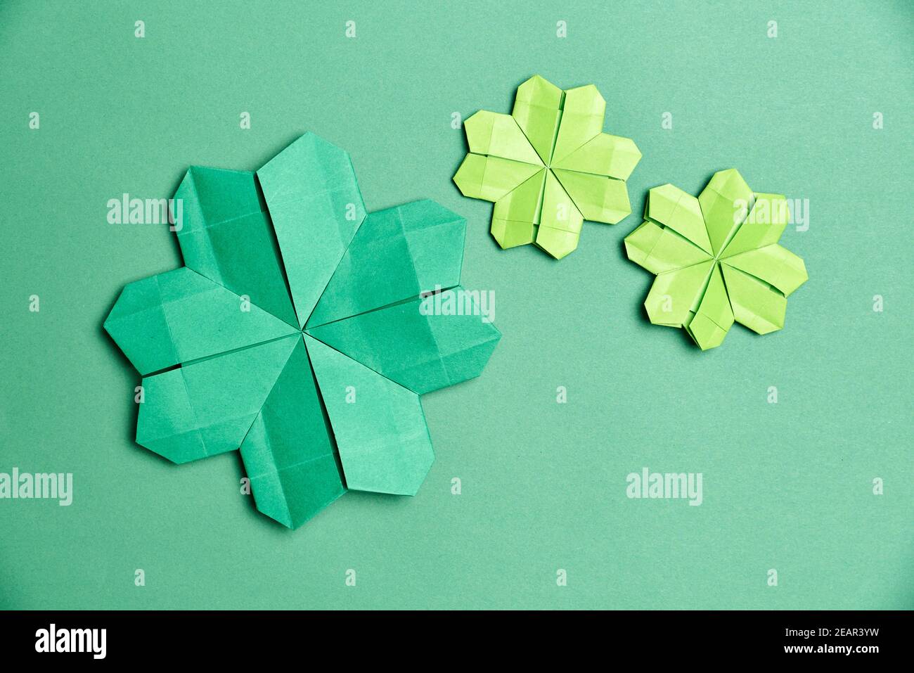Shamrocks à quatre feuilles d'origami, en papier vert, sur fond vert. Concepts de chance et de la Saint-Patrick. Image avec espace de copie. Banque D'Images
